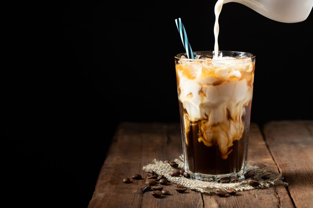 Ice Coffee In A Tall Glass With Cream Poured Over And Coffee Bea